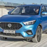 Niebieski MG ZS Classic jedzie po zaśnieżonej drodze. Kierowca w okularach prowadzi auto.
