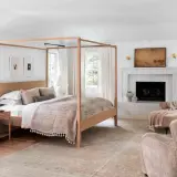 A cozy bedroom with a four-poster bed, fireplace, and plush seating, perfect for romance in bed.