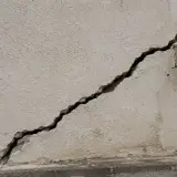 Une fissure importante traverse la façade d'un bâtiment, nécessitant une réparation urgente.