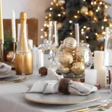 Festlich gedeckter Tisch Weihnachten mit goldenen Kugeln, Kerzen und Champagner. Ein eleganter Blickfang für die Feiertage.