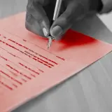Dłoń podpisuje umowę o współpracę między firmami. Dokument zawiera pola na datę i podpisy.