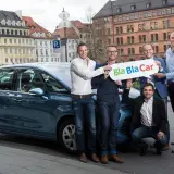 Zespół prezentuje, jak działa BlaBlaCar, stojąc obok samochodu.