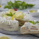 Delicioso postre de limón con leche condensada y galletas, decorado con crema batida, rodajas de limón y menta.
