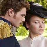 Młody mężczyzna w mundurze i kobieta w kapeluszu, przypominający obsadę filmu o cesarzowej Sisi, patrzą w różne strony.
