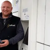 Uśmiechnięty kurier InPost trzyma skaner. Zastanawiasz się, ile zarabia kurier InPost?
