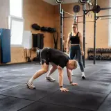 Trenerka obserwuje mężczyznę wykonującego burpee, ćwiczenie znane z intensywności.