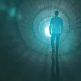 Mężczyzna idzie w stronę jasnego światła w tunelu, doświadczając widzenia tunelowego.