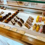 Witryna cukierni z wykwintnymi deserami, w tym makaronikami i ciastkami, idealna dla szukających najlepszych francuskich restauracji.