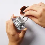 Ręce montują łącznik dwubiegunowy do ściany, podłączając przewody do mechanizmu.