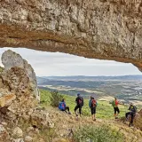Senderistas disfrutan de vistas panorámicas en rutas por Navarra, bajo un arco natural de roca.