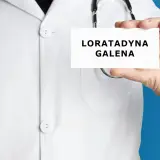 Lekarz trzyma kartkę z napisem "LORATADYNA GALENA". Stetoskop wisi na jego białej katanie.