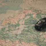 Czarny samochodzik na mapie Europy, szukający drogi do Mikołajek.