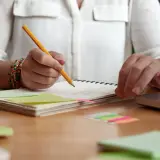 Person plant den **Aufbau einer Unterrichtsstunde** mit Notizen, Büchern und einem Laptop.