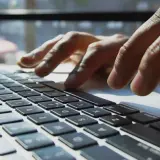 Mains sur un clavier d'ordinateur portable, une tasse de café à proximité. L'utilisateur interagit avec un chatbot helpdesk pour obtenir de l'aide.