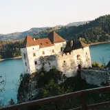 Niedzica-zamek trasa: malowniczy zamek na skale nad turkusową wodą, otoczony zielonymi wzgórzami.