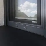 Szary parapet zewnętrzny pod oknem z moskitierą. Zastanawiasz się, czym przykleić parapet zewnętrzny blaszany?