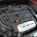 Silnik TSI z widocznym logo VW. Widoczne elementy układu dolotowego i osłony silnika.