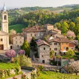 Borgo pittoresco con chiesa e campanile, colline verdi e fiori in primavera. Un luogo incantevole da scoprire, un vero gioiello per chi cerca cosa vedere a Golferenzo.