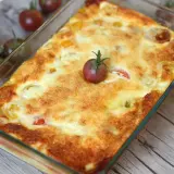 Un clafoutis tomates cerises doré et appétissant, garni d'une tomate cerise fraîche, prêt à être dégusté.