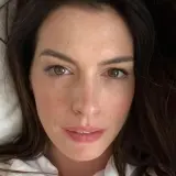 Zbliżenie na twarz Anne Hathaway. Aktorka ma brązowe oczy i ciemne włosy. Wiele osób zastanawia się, ile lat ma Anne Hathaway, ale na tym zdjęciu wygląda młodo i promiennie.
