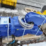 Solidne nożyce hydrauliczne do koparki, gotowe do pracy. W tle żółte i pomarańczowe łyżki.