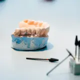 Model szczęki, na którym powstaje proteza elastyczna, obok narzędzi dentystycznych.