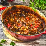 Herzhaftes Kalbsgulasch im roten Bräter, ein köstliches Rezept mit Paprika und Zwiebeln, bereit zum Servieren.