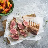 Un délicieux carré d'agneau au barbecue, coupé en côtelettes rosées, servi avec des poivrons grillés.
