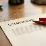 Czerwony długopis obok dokumentu z nagłówkiem "UZASADNIENIE" sugeruje przygotowanie do formalnego rozwiązania umowy o pracę.