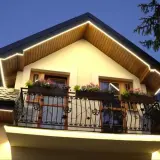 Eleganckie oświetlenie podbitki schemat podkreśla architekturę domu. Ciepłe światło LED tworzy przytulną atmosferę wieczorem.
