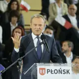 Donald Tusk przemawia na konwencji po w Płońsku. W tle widzowie z polskimi flagami.