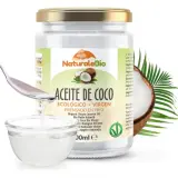 Un frasco de aceite de coco ecológico y virgen, ideal para el cuidado del pelo. Una cuchara vierte el aceite en un cuenco.