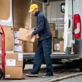 Zusteller lädt Pakete aus einem Lieferwagen. Viele Pakete, vielleicht wegen des peak season surcharge.