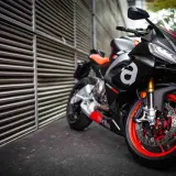 Aprilia RS 660, una moto deportiva negra con detalles rojos y naranjas, lista para la acción.