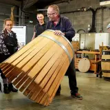 Visite tonnellerie Bourgogne : un maître tonnelier montre un fût en cours de fabrication à des apprentis.