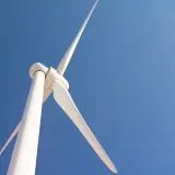 Biała turbina wiatrowa bez pozwolenia na tle błękitnego nieba.