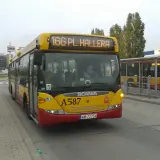 Żółty autobus linii 166 w Warszawie, z numerem bocznym A587, zbliża się do przystanku obok centrum handlowego Tesco.