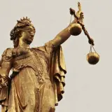 Złota statua Temidy z przepaską na oczach i wagą w dłoni, symbol sprawiedliwości, która może być utrudnianie korzystania z lokalu.