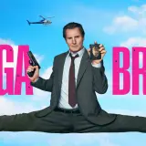 Liam Neeson w filmie "Naga broń" w akcji, z pistoletem i odznaką policyjną. W tle helikopter.