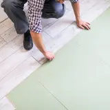 Układanie podłogi pływającej, co to jest? Montaż paneli laminowanych na zielonym podkładzie.