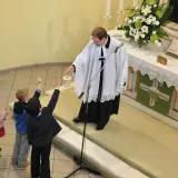 Dzieci na nabożeństwie w kościele luterańskim. Ksiądz z kadzielnicą błogosławi zgromadzonych.