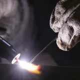Un soldador usa una antorcha para crear una chispa brillante, demostrando que es la soldadura.