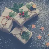 Julklappar inslagna i brunt papper, dekorerade med granris och stjärnor, redo för Siggesta Gård julmarknad.