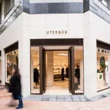 Fachada de tienda UTERQÜE con escaparates y entrada abierta. Una persona pasa por delante.