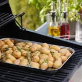 Un plateau de pommes de terre nouvelles assaisonnées d'herbes, prêtes pour le barbecue.