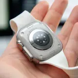 Naprawa smartwatcha Apple Watch Ultra. Widok na tył zegarka z białym paskiem, trzymanego w dłoni.