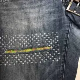 Close-up of denim jeans with a colorful fabric patch and white cross-stitch embroidery, showcasing a stylish sashiko jeans repair.