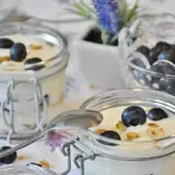 Dwa słoiczki z jogurtem naturalnym, jagodami i granolą. Pyszne śniadanie, które może pomóc w walce z cholesterolem.