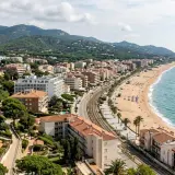 Vista aérea de una ciudad costera con edificios, playa y mar azul. Las **zenhotels opiniones** de este lugar sugieren una estancia relajante.