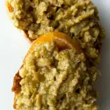 Deux tranches de pain garnies d'une généreuse portion de tapenade verte, prêtes à être dégustées.